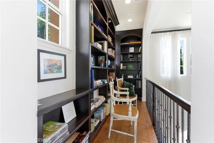 Upper-level library loft with custom built-in shelving overlooking the main living area, creating a refined space for reading, work, or display.