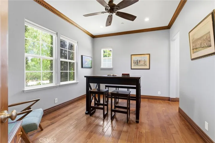 Main-level office/bedroom with rich hardwood flooring and adjacent full bath