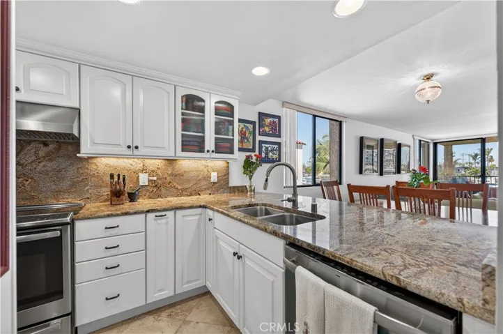 Remodeled kitchen with granite counters, glass fronted cabinets, stainless appliances and a view of the water.
