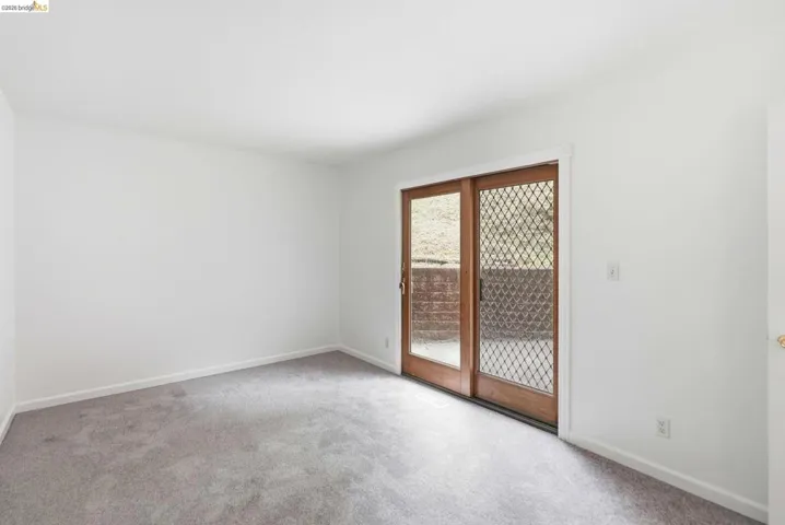 Carpeted room with white walls, baseboard trim, and a sliding glass door with wood frames