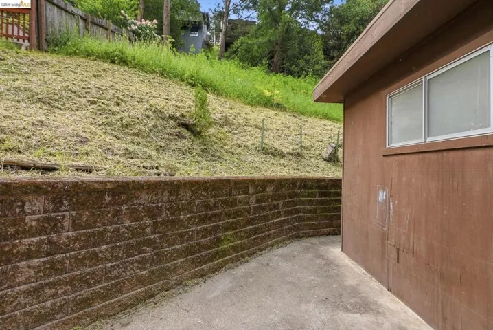 Concrete hardscaping with a retaining wall, complemented by a brown-sided structure featuring a double-pane window