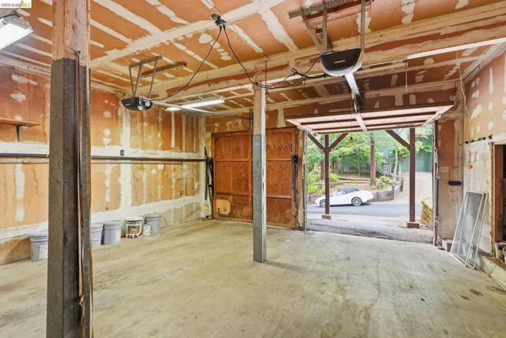 Two-car garage space featuring concrete flooring, exposed ceiling joists, and a partial wood door