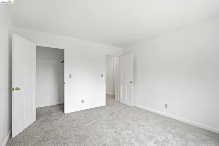Room featuring light gray carpeting, white walls, white baseboards, and white trim around doorways