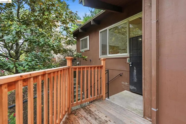 Exterior entryway featuring a wood deck, wooden railing, and a black security screen door