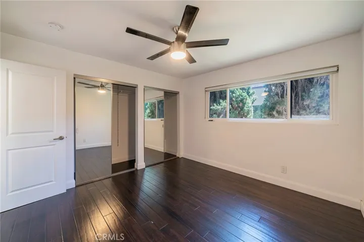Second bedroom with large mirrored closet doors, ceiling fan and window for breezes