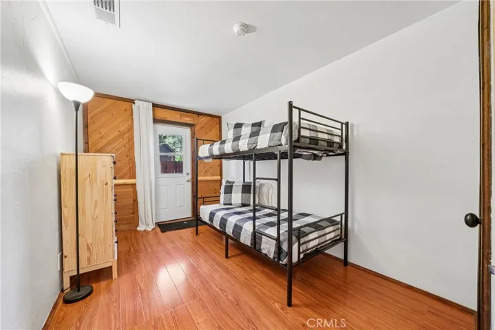 Flexible sleeping space or guest room with backyard access and warm wood accents.