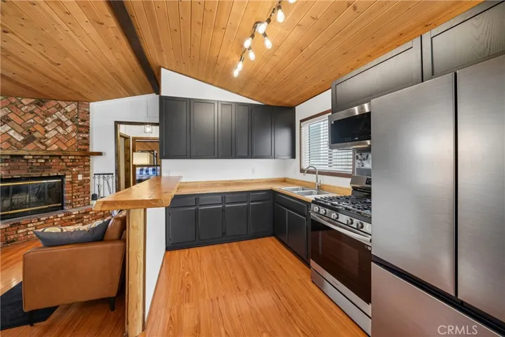 Updated kitchen with stainless appliances, bespoke wood counters, and black cabinetry.