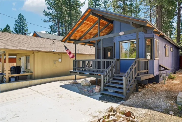 Charming Big Bear Lake home with expansive covered front deck and warm wood roof detail.