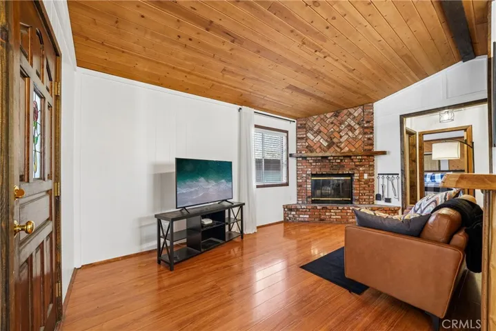 Open living area with tongue-and-groove wood ceiling, brick fireplace, and warm mountain style.