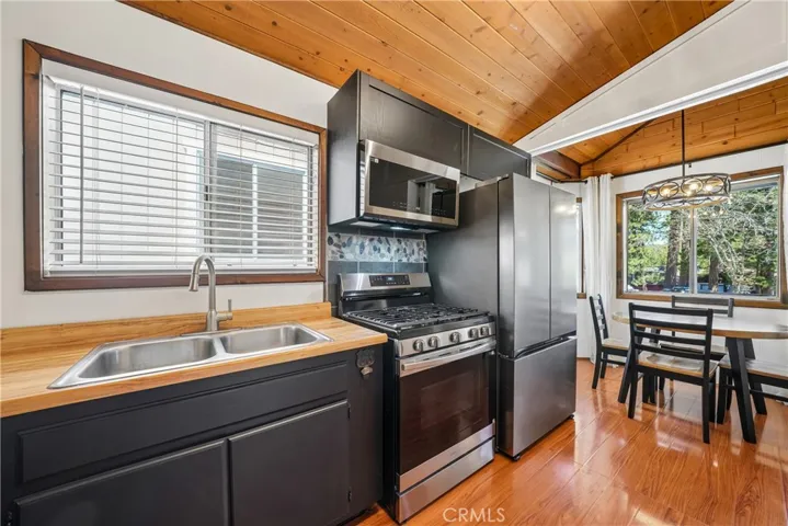 Kitchen view showing stainless appliances, wood counters, and dining area beyond.