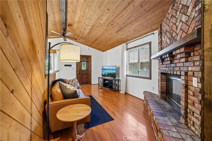 Living room with brick fireplace, vaulted wood ceiling, and comfortable mountain-home character.