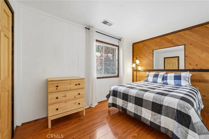 Bedroom with wood accent wall, warm floors, and clean mountain-modern styling.