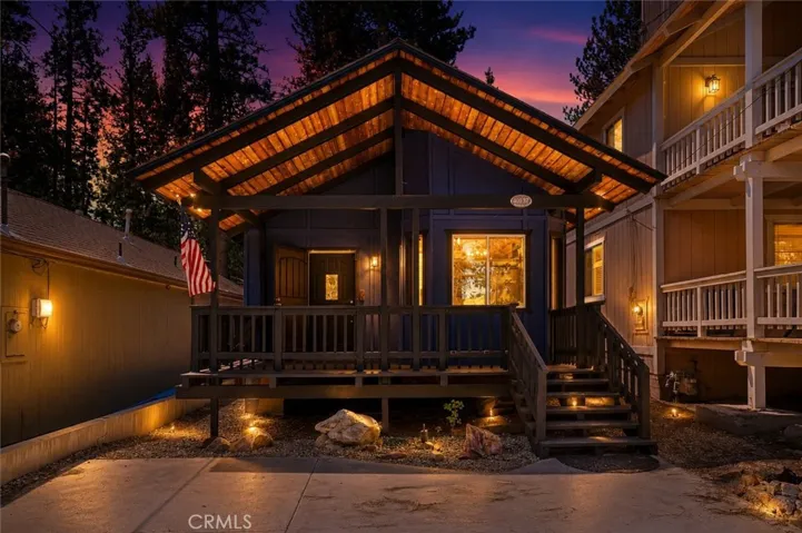 Twilight-enhanced exterior view highlighting the covered front deck and warm evening ambiance.