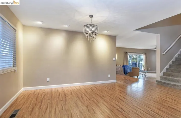 Empty room featuring stairway, light wood finished floors, and a chandelier