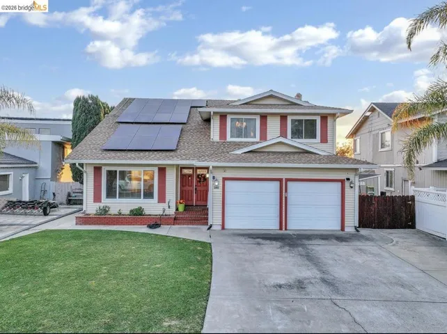 View of front facade with roof mounted solar panels, concrete driveway, an attached garage, and a shingled roof