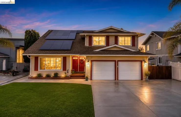Two-story residence featuring light-toned siding, a two-car garage, and red accent shutters