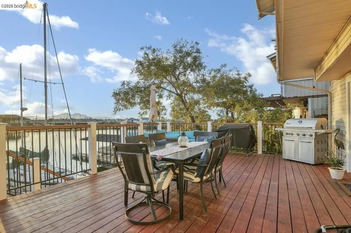 Wooden terrace featuring area for grilling, a water view, and outdoor dining space