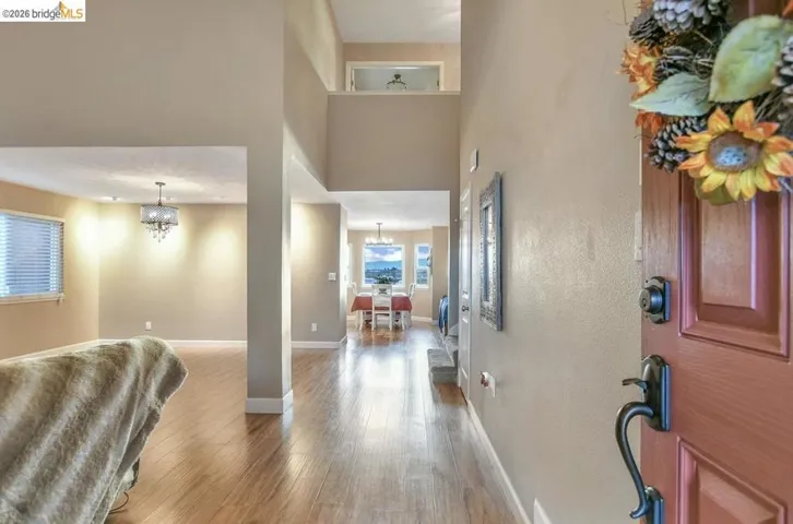 Foyer with a towering ceiling, light wood-style floors, and a chandelier