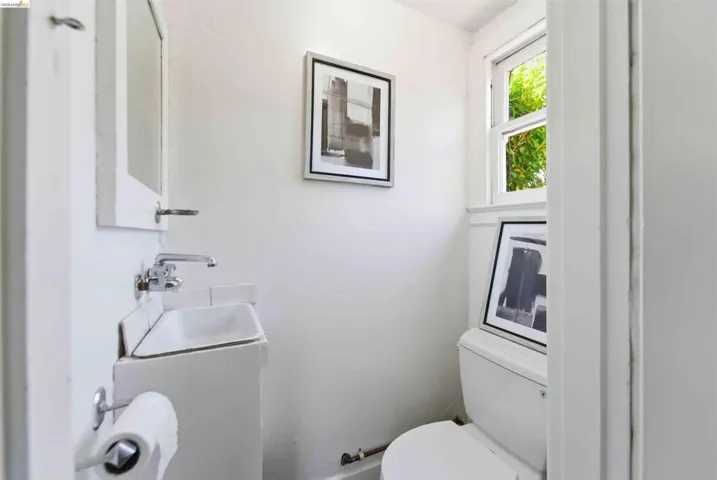 Compact powder room with a wall-mounted sink, chrome faucet, and a window providing natural illumination
