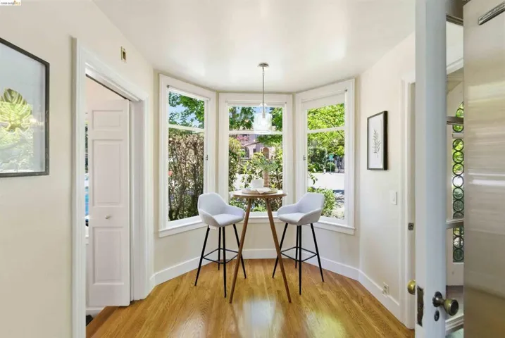 Breakfast nook featuring a bay window, hardwood flooring, pendant lighting, and white trim