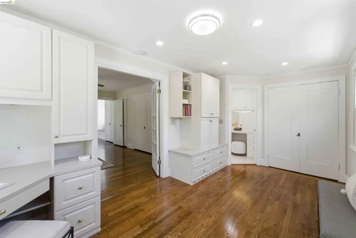 Spacious room featuring wood-finish flooring and white crown molding