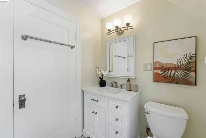 Bathroom featuring a white single-sink vanity with a light-colored countertop, wall-mounted mirror, and three-light vanity fixture