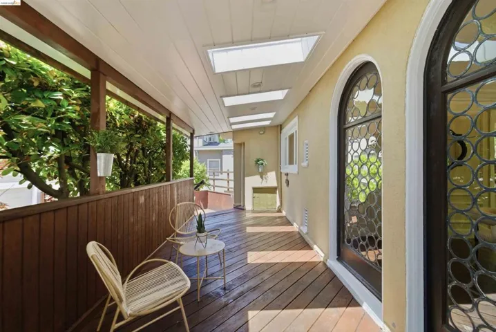 Covered porch with wood-finish flooring, wood railing, and white plank ceiling featuring multiple skylights