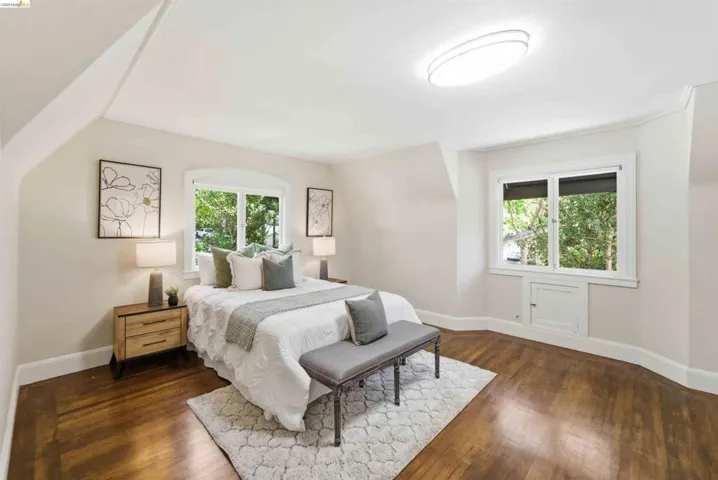 Hardwood flooring extends throughout this room, featuring multiple windows with white trim, a built-in storage cabinet, and a contemporary ceiling fixture