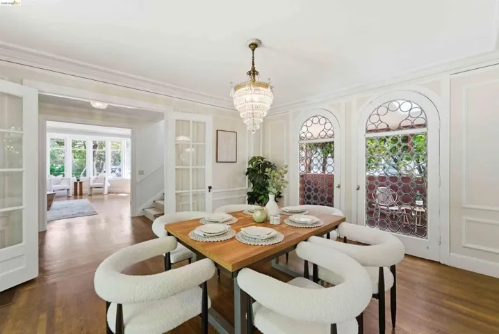 Formal dining space featuring wood-finish flooring, an ornate chandelier, and detailed wall paneling