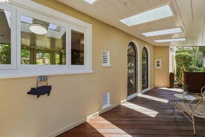 Covered outdoor space featuring wood-finish flooring, multiple skylights, and two arched doorways with decorative glass