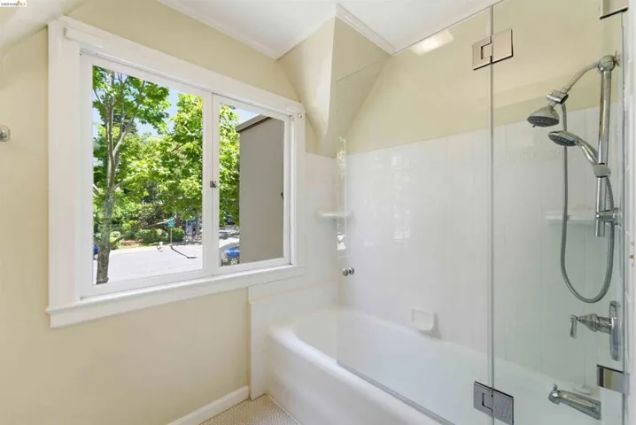 Bathroom featuring a full-size bathtub with a glass shower partition, dual shower heads, and white tiled walls