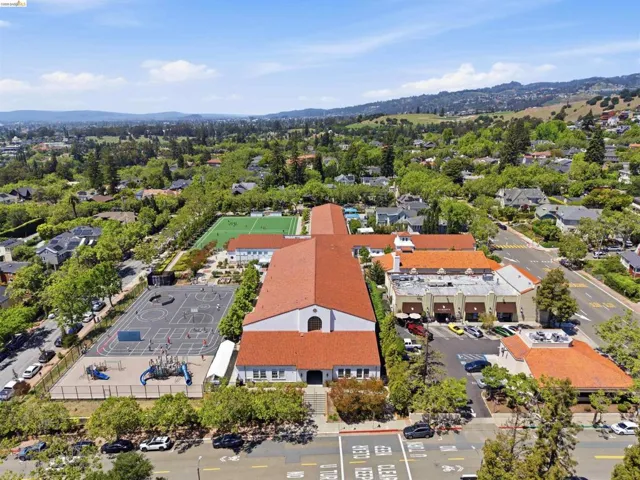 Expansive property featuring multiple buildings with terra cotta tile roofs, a large athletic field, and a dedicated playground area