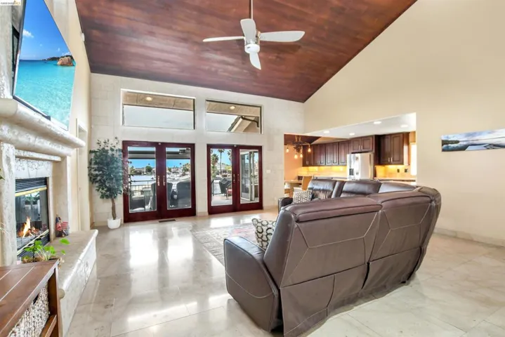 Living room featuring vaulted wood-paneled ceiling, ceiling fan, and light-toned tile flooring