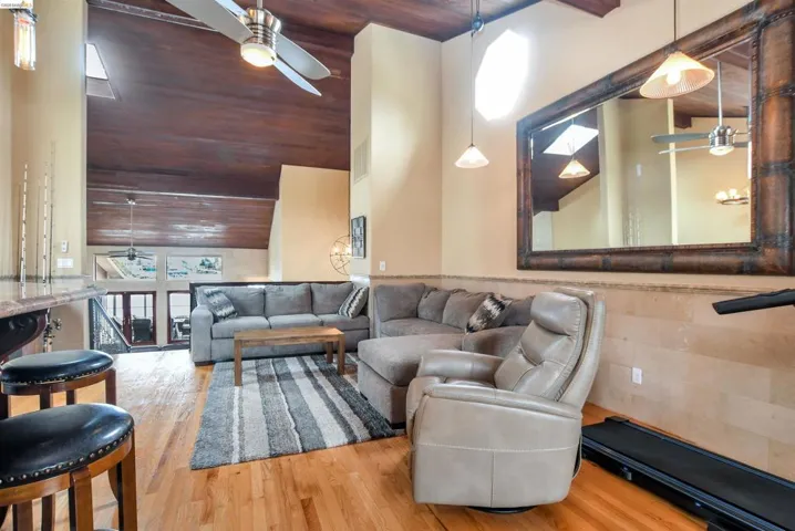 Open-concept living area featuring a vaulted wood-finish ceiling, hardwood flooring, and a two-story wall with upper windows