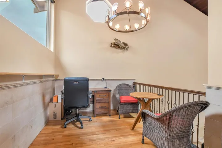 Loft area featuring hardwood flooring, an octagonal skylight, and a wrought iron chandelier