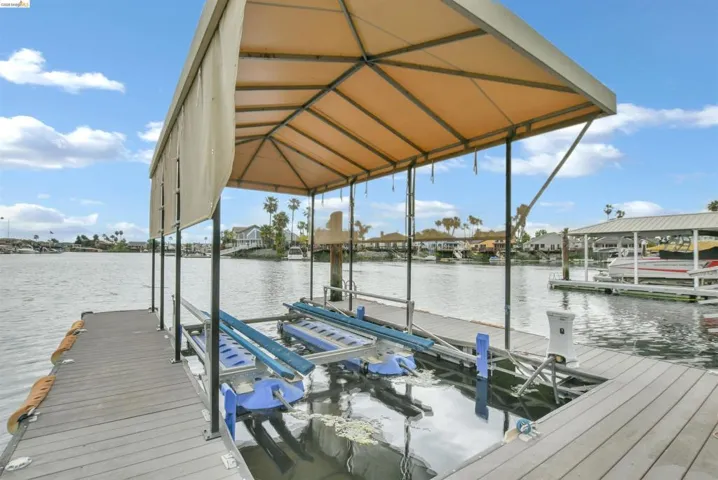 Private dock featuring composite decking, an overhead canopy, and a boat lift