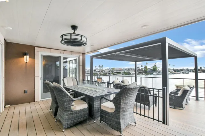 Expansive covered deck featuring wood-finish flooring, a ceiling fan with integrated lighting, and a modern pergola structure