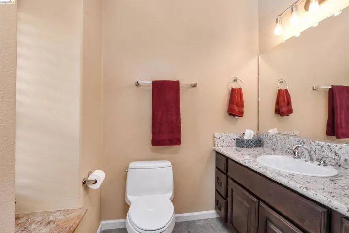 Bathroom vanity featuring a granite-style countertop, undermount sink with a chrome faucet, and dark wood-finish cabinetry