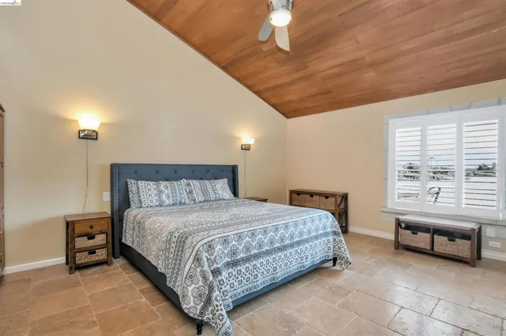 Vaulted wood-finish ceiling with a ceiling fan, complemented by light-toned wall sconces