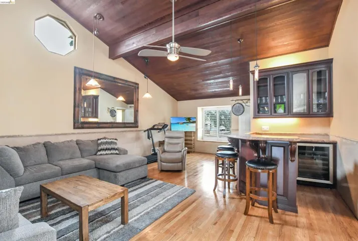 Wood-finish vaulted ceiling featuring exposed beams and a ceiling fan