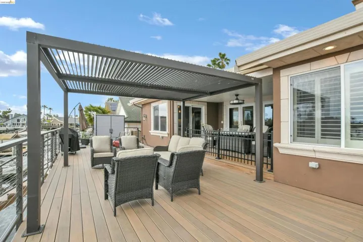 Spacious outdoor deck featuring wood-finish flooring, a louvered pergola, and cable railing
