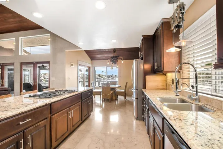 Gourmet kitchen featuring granite countertops, built-in gas range, dark wood cabinetry, and recessed lighting