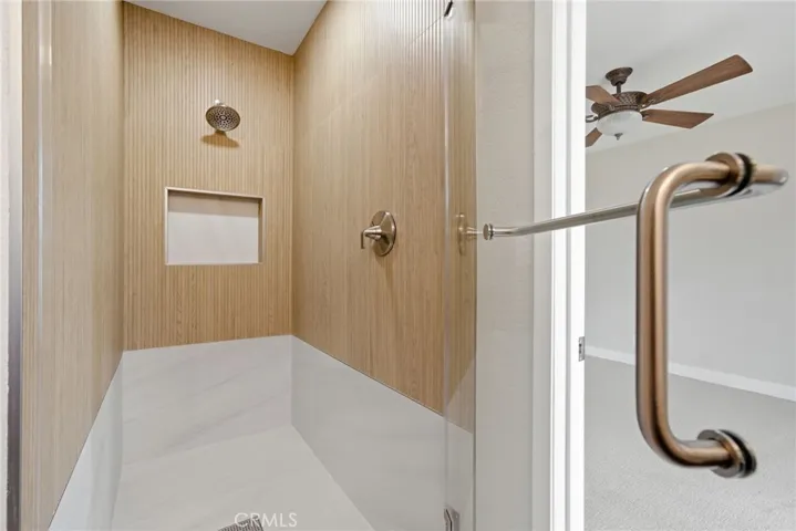 Walk-in shower finished with large-format porcelain tile.