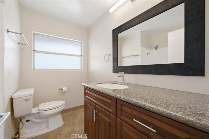 Hall bath features cherry-toned cabinetry and tile flooring.