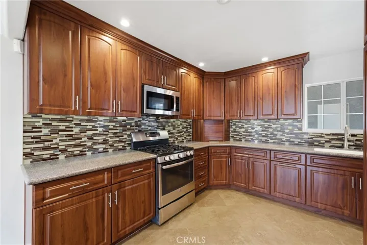Well-appointed kitchen with cherry-toned cabinetry and stone countertops.