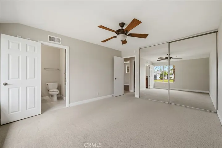 Spacious primary suite with carpet flooring and ceiling fan.