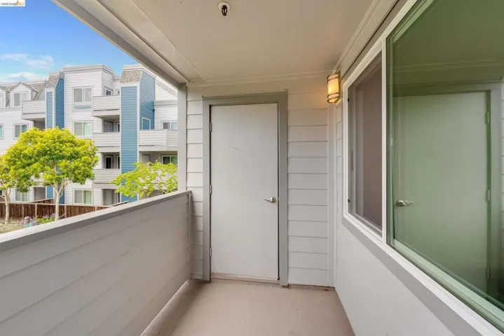 Private outdoor balcony featuring a painted concrete floor and a solid privacy wall