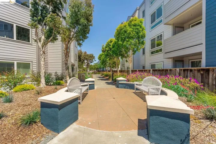 Landscaped courtyard featuring a paved walkway, built-in benches, and mature trees