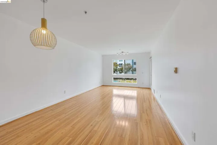 Bright interior with wood-finish flooring, white walls, and a modern pendant light fixture
