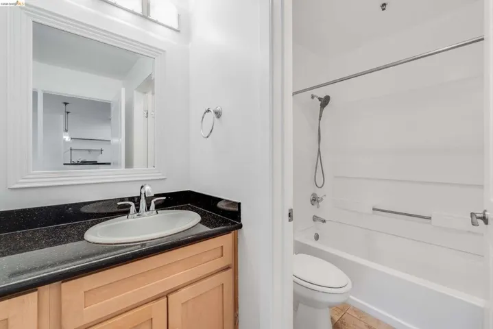 Bathroom featuring a wood-finish vanity with a dark speckled countertop and an undermount sink